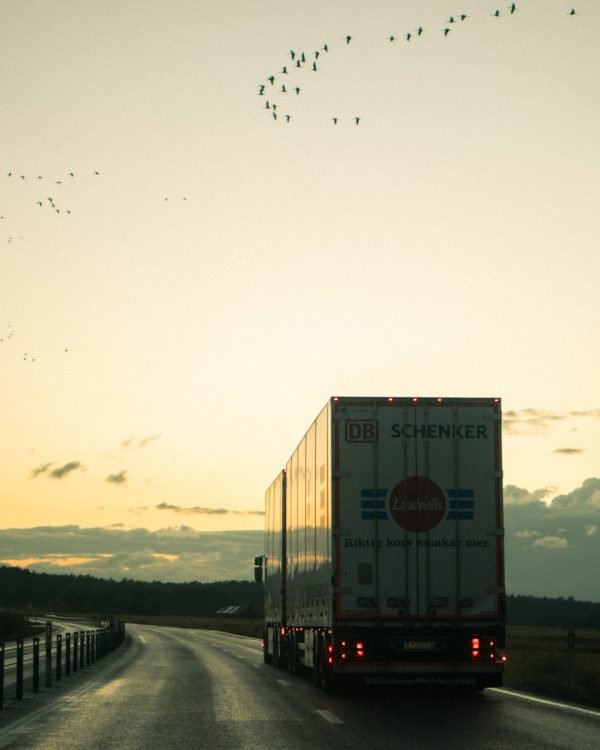 photo by jeremi joseph a semi truck driving down a road at sunset